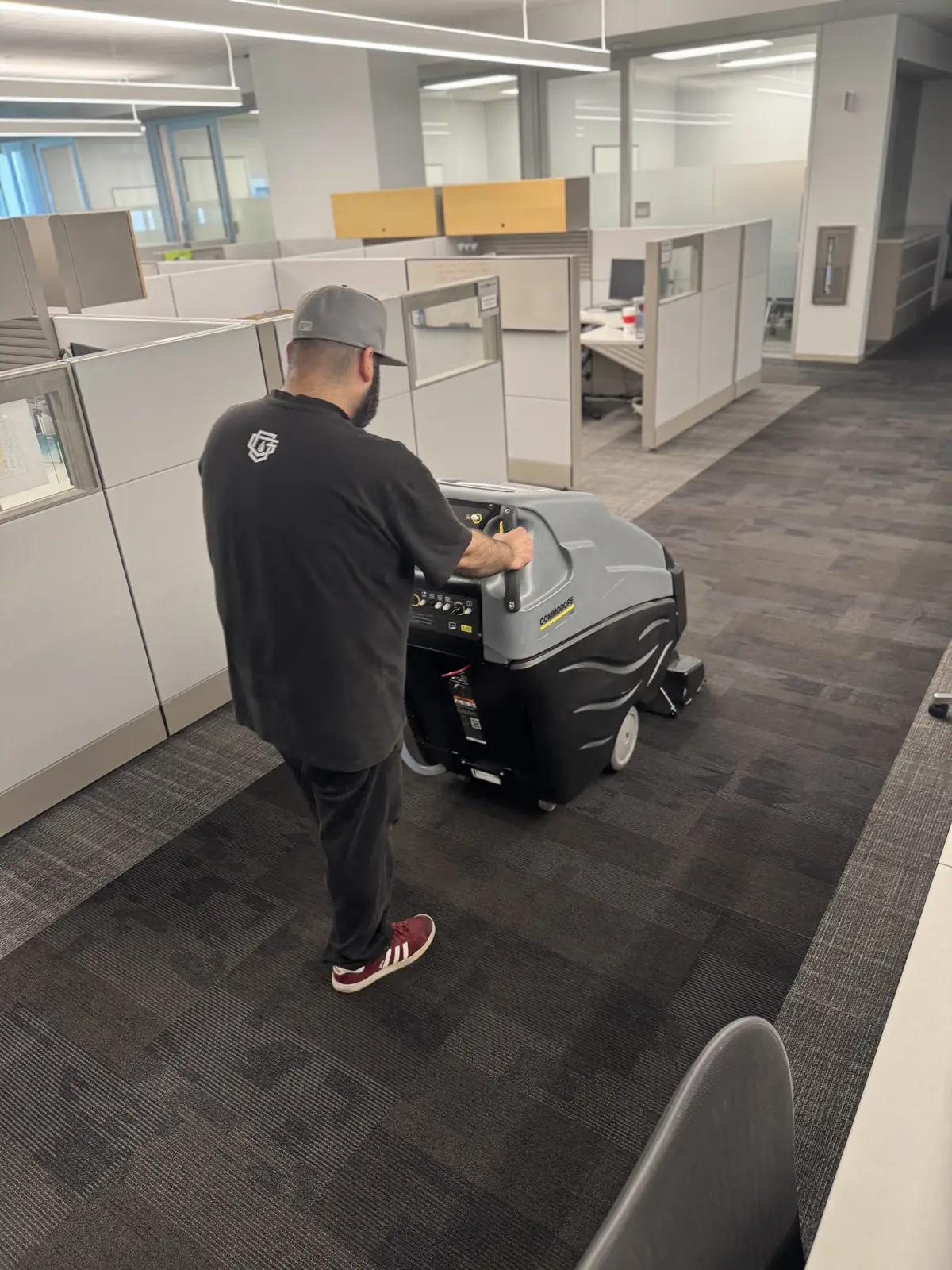Crew member extracting carpet between office cubicles