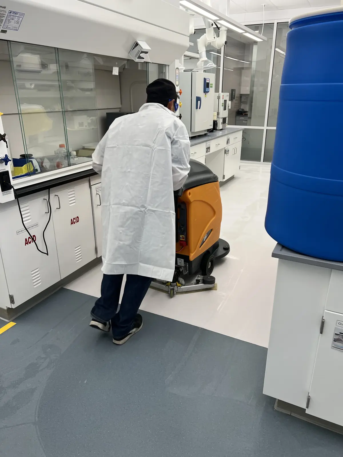 Gowned technician operating an auto-scrubber in a laboratory