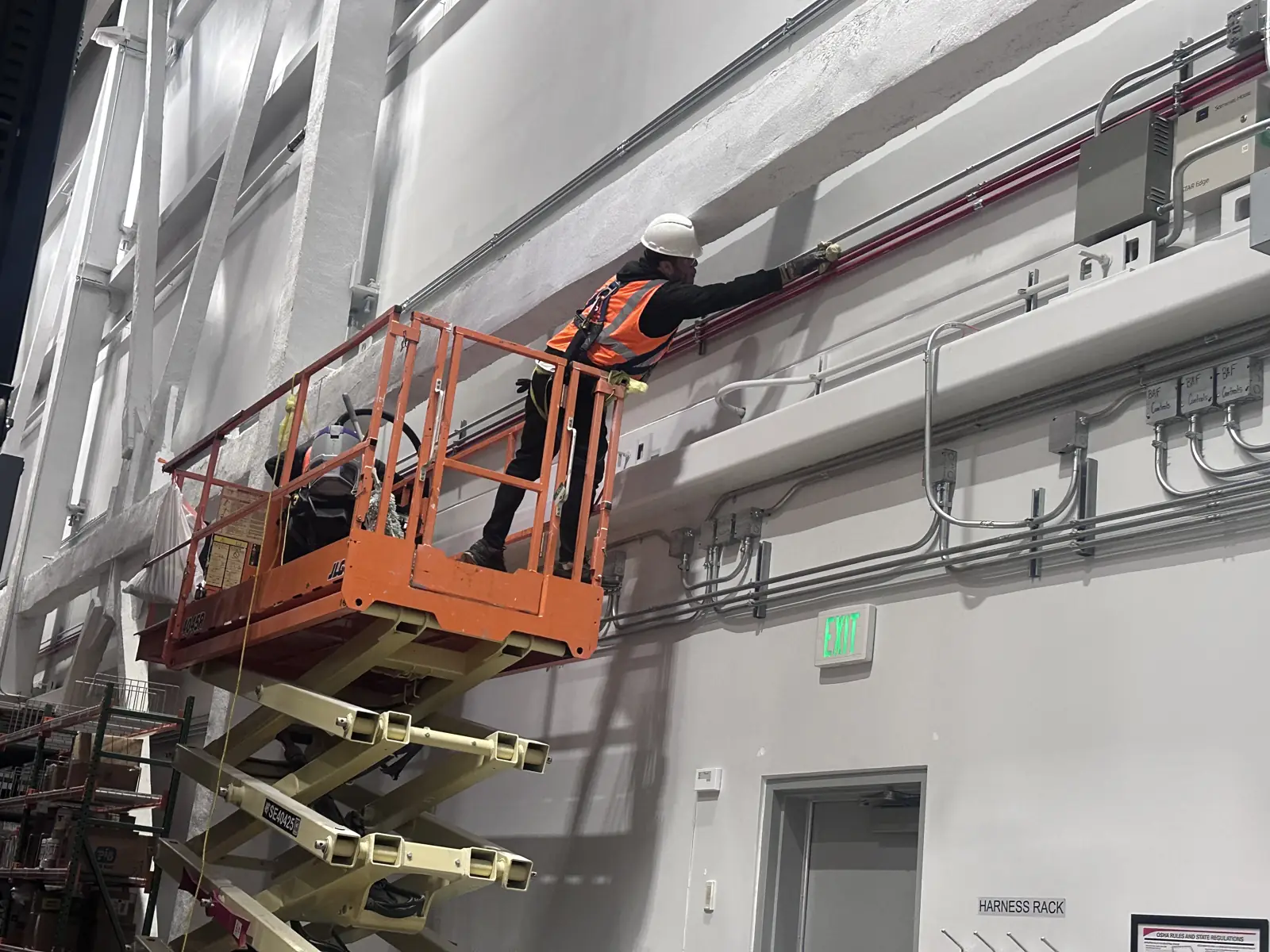 Crew on a scissor lift cleaning a high warehouse wall
