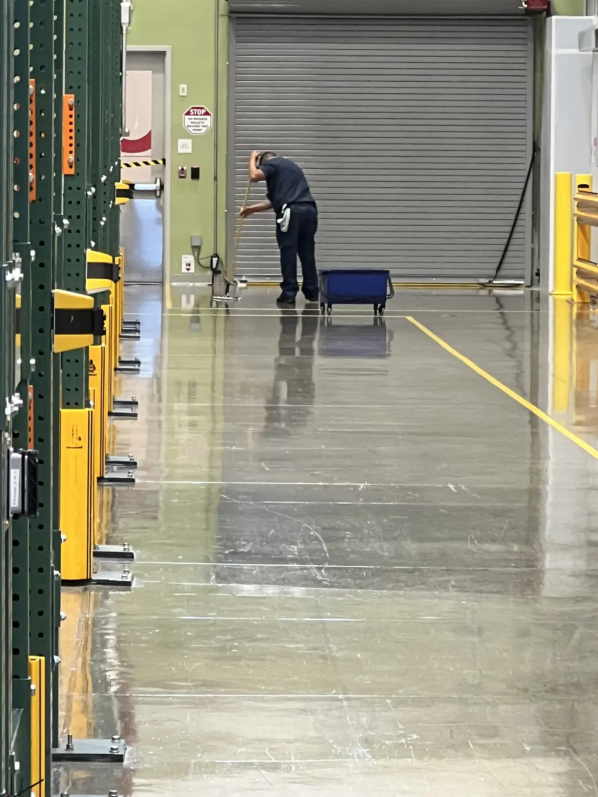 Nexara crew member mopping a polished concrete aisle beside pallet racking