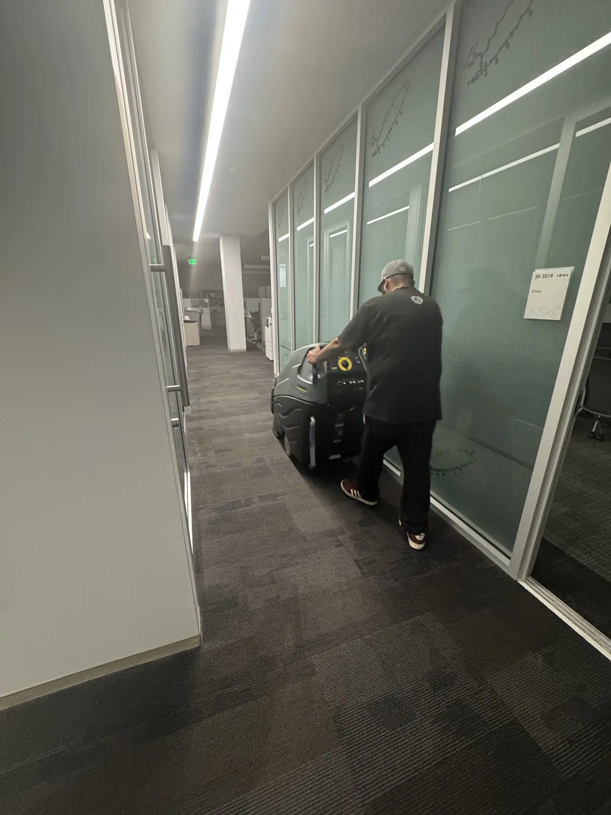 Nexara crew cleaning carpet outside a glass-walled conference room