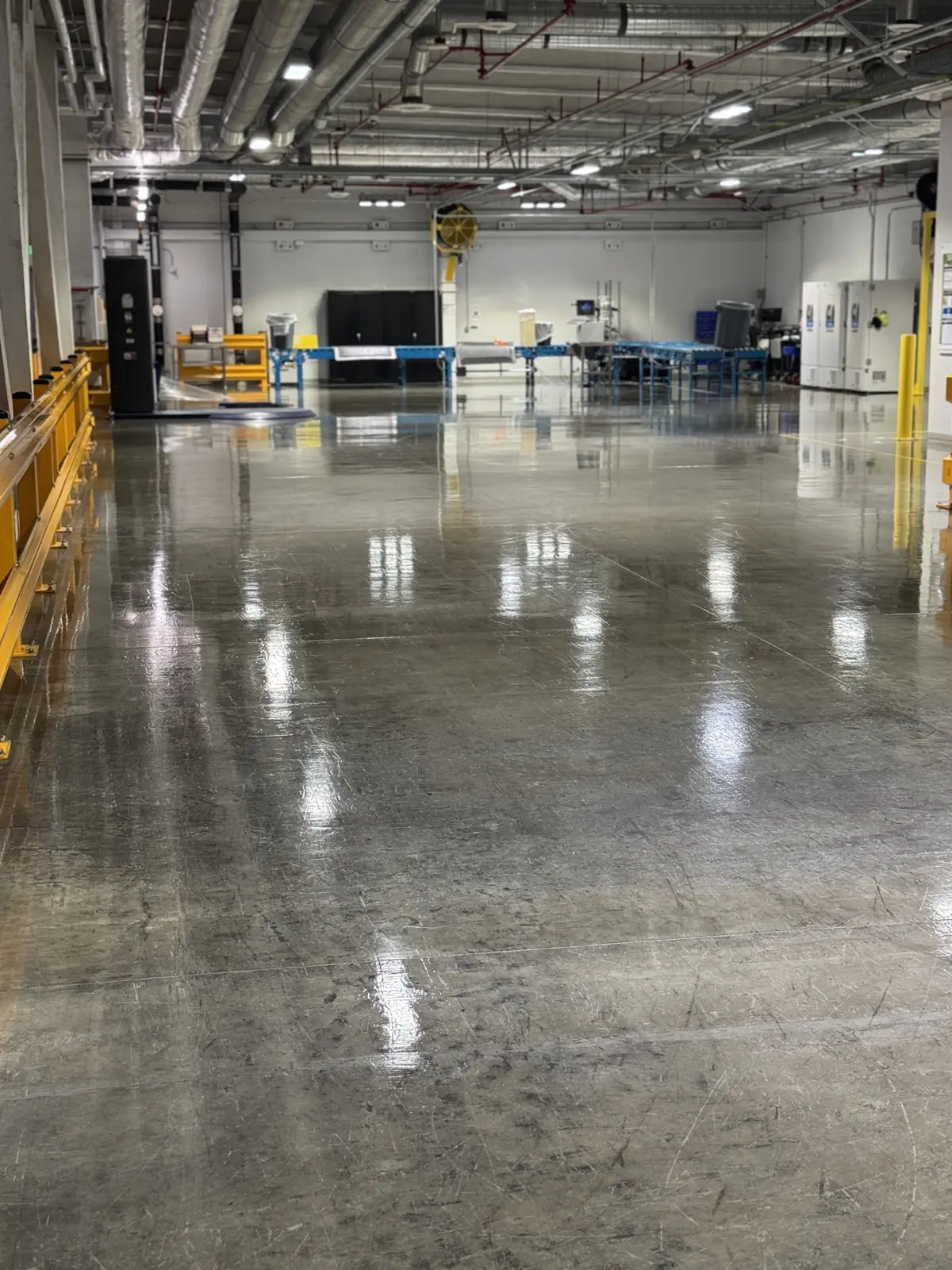 Large polished concrete facility floor reflecting overhead lights